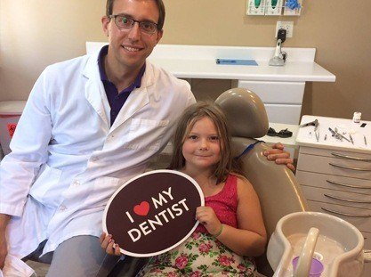 Dentist team members and smiling patient in dental exam room